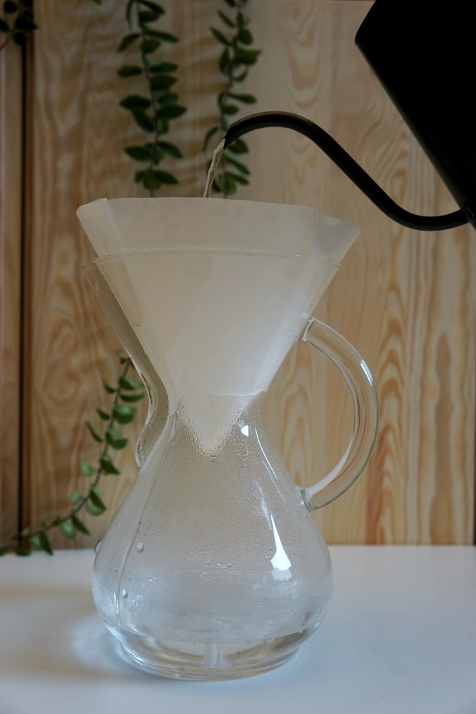 aby parzyć kawę w chemex zalej ziarna kawy gorącą wodą
